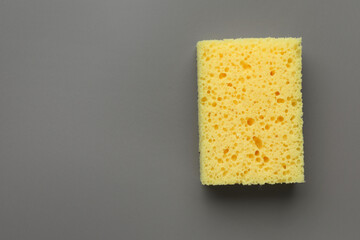 New yellow sponge on grey background, top view. Space for text