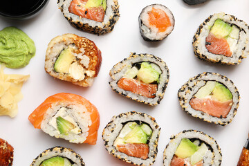 Different tasty sushi rolls on white background, flat lay
