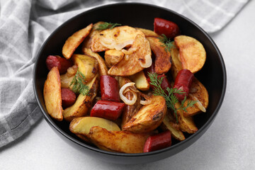 Delicious baked potato with thin dry smoked sausages, onion and dill in bowl on gray table, closeup