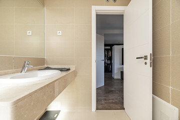 Bathroom with porcelain sink embedded in a marble countertop and a mirror integrated into the wall