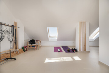 An attic of a residential house with a gym located on the upper floor with skylights and stacked...
