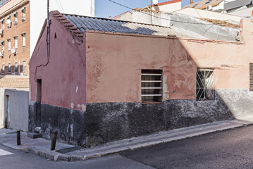 A low house with shabby facades on a street corner with very narrow sidewalks