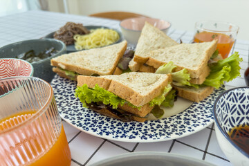 Happy Asian woman enjoy eating a homemade sandwich and drinking black coffee in morning at home.