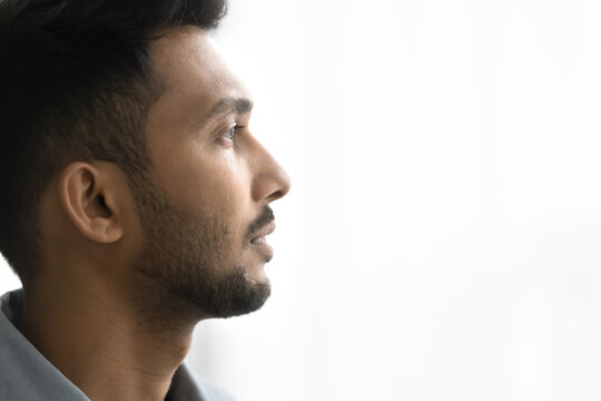 Close up profile face view of pensive Indian man with attractive appearance, well-groomed beard looks into distance posing on white grey copy space background for your text. Thoughts, memories, quotes