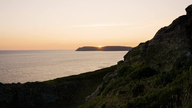 The sun sets behind coastal hills looking over beautiful ocean views