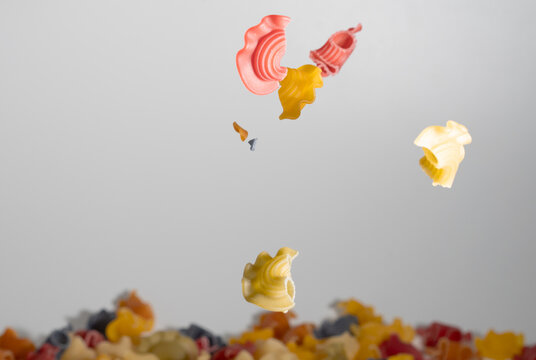 Falling raw multocolor  Creste di gallo, uncooked Italian Pasta on bowl and sackcloth