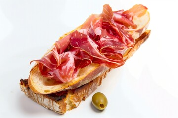 Cured prosciutto sandwich in a toasted baguette bread  (bocadillo de jamon serrano) on white background