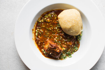 Overhead view of Nigerian okro and stew with eba in a white plate, top view of okro soup and eba