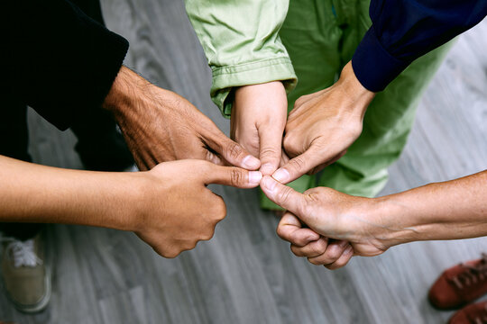 A collaborative standing team giving thumbs up with circle shape close up