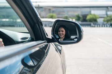 Side and rear view mirror. Close up shot face of young asian business woman looking rear view mirror roadway while driving car in the morning. Business women getting new car driving on the road