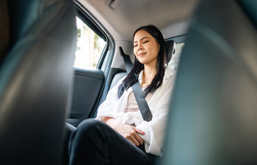 Relaxing moment of beautiful woman sleeping in car back seats with safety belt. Female happy in car while traveling on the road to destination.