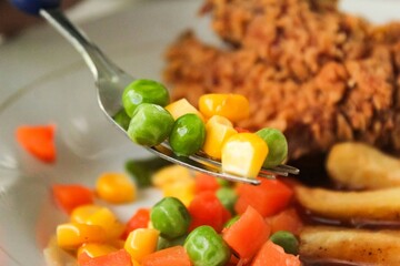 a fork that picks up vegetables on a plate