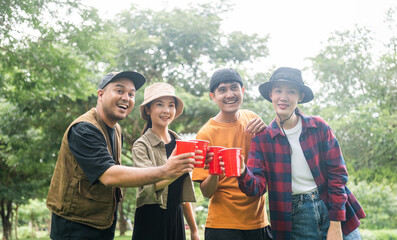 Cheers! Group of asian people friend party camping in nature making toasting with soft drink and beer red cup. Hangout party outdoor in campsite nature forest background on holiday weekend vacation
