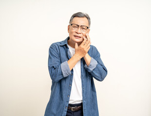 Old man senior puts his hand on his mouth and feels toothache because of tooth decay. Problems with teeth bad breath. Mature man unwell unhealthy standing on isolated background