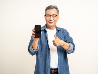 Handsome asian mature old man using smartphone showing screen display on isolated white background. Portrait of cheerful smiling senior asian man holding cell phone. Mature People and lifestyle