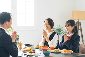 食卓でいただきますして手をあわせる親子
