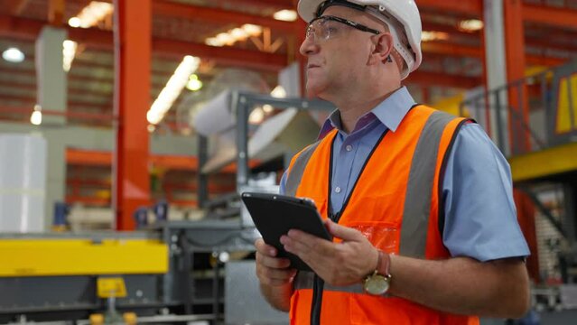 American older Engineer or worker wear hard Hat working in a factory with heavy machinery. Industrial Specialist Standing in Metal Construction Manufacturing technicians assistant workers in warehouse