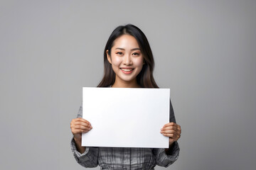 Naklejka premium Smiling Young asian woman showing and holding blank white billboard