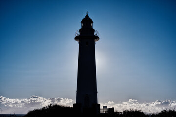 冬の低い太陽と岬に建つ灯台
