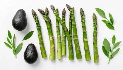 Poster Green herbs, asparagus and black avocado on a white background © Lupu