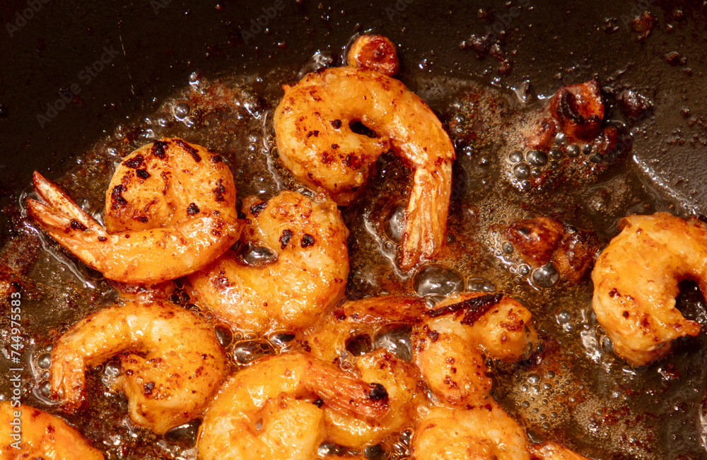 Poster shrimp are fried in a frying pan in oil