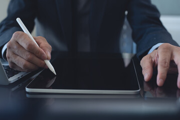 Businessman, manager working, using stylus pen signing e-document on digital tablet with laptop computer on table at modern office, e-signing, electronic signature, work planning