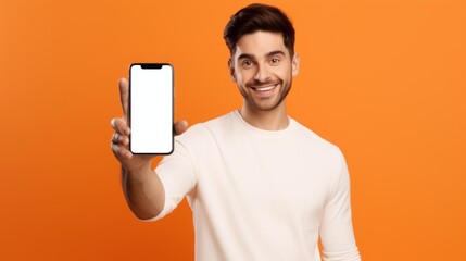 A Handsome Smiling Man Pointing At A White Blank Smartphone Screen on An Orange Background. A mock-up of a mobile phone Display with an empty space, Advertising a Mobile Application, Discounts, Sales.