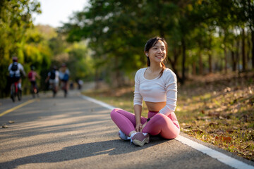 A young woman sits on the road to rest after jogging.