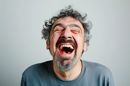 A man with raised eyebrows and a twisted mouth trying to hold back laughter on a white background