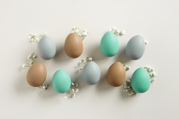 Easter Aesthetic with Matte Eggs and Delicate Florals, painted chicken egg decorated white flowers, top view on beige background, spring holiday concept. Minimal style pattern in pastel tones