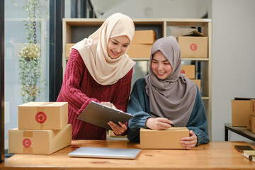 Friend muslim female two work business sme online shopping working on laptop computer with parcel...