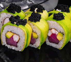 Sushi roll covered with avocado with tuna and black caviar