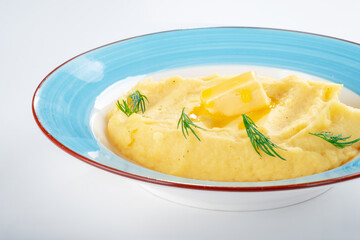 Homemade mashed potatoes, with butter and dill, on a plate against a white background, close up
