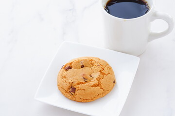 チョコレートがたっぷり入ったチョコチップクッキーとコーヒーでおやつの時間
