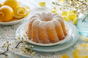 Easter lemon bundt cake, Babka sprinkled with icing sugar on a festive table decorated with spring flowers, close up view - 745002958
