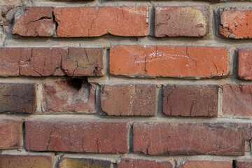 Close-up view of old molded red brick wall covered with craters from military shells, bullets, cracks and scratches. Copy space for your text and decorations. Soft focus. Aftermath of the war theme.