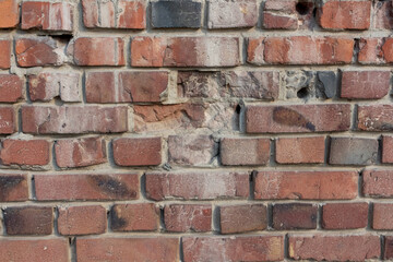 Close-up view of old molded red brick wall covered with craters from military shells, bullets, cracks and scratches. Copy space for your text and decorations. Soft focus. Aftermath of the war theme.