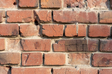 Fototapeta premium Close-up view of old molded red brick wall covered with craters from military shells, bullets, cracks and scratches. Copy space for your text and decorations. Soft focus. Aftermath of the war theme.