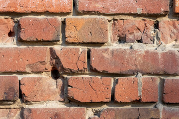 Close-up view of old molded red brick wall covered with craters from military shells, bullets,...