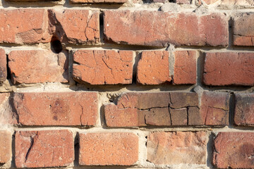 Close-up view of old molded red brick wall covered with craters from military shells, bullets, cracks and scratches. Copy space for your text and decorations. Soft focus. Aftermath of the war theme.