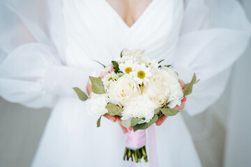 Obraz na płótnie Canvas Bride in white dress holding white flower bouquet at wedding ceremony