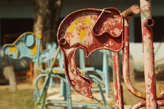 Close up of a red rocking horse made of steel is made in the shape of a red elephant in an outdoor playground in Thailand.
