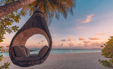 Beautiful silhouette of hammock on palm trees on tropical beach paradise at sunset. Carefree...