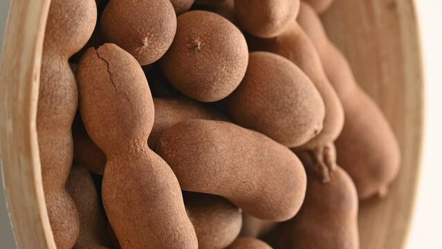 Closeup of a heap of tamarind fruit pods rotating on the turntable.