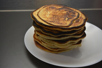 A hearty breakfast, deliciously prepared homemade food, lots of big, fluffy pancakes are arranged on a large white plate.