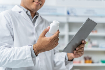 Medical pharmacy and healthcare. Close up male pharmacist wearing lab coat holding pill bottle and...