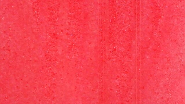 Drops of condensation on the ice cream tank. Ice cold sorbet machine mixing fruit juice. Freezing slush spinning around, summer treat. Crushed iced coloured with fruit flavor sweeteners 
