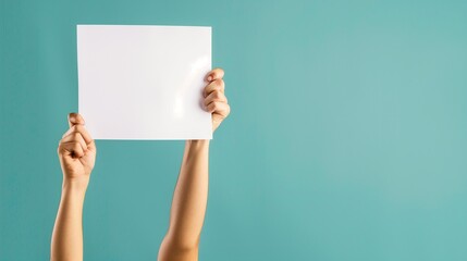 Hands holding blank sign. Concept of a person's arms raised up, presenting a white empty paper against a turquoise background, suggesting a space for text or advertisement. - obrazy, fototapety, plakaty