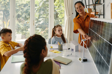 Group of kids listening to teacher talking about solar energy when showing panel