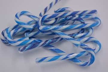 Happiness, joy, sweets, New Year candies, Christmas white lollipops with blue stripe arranged on white background.